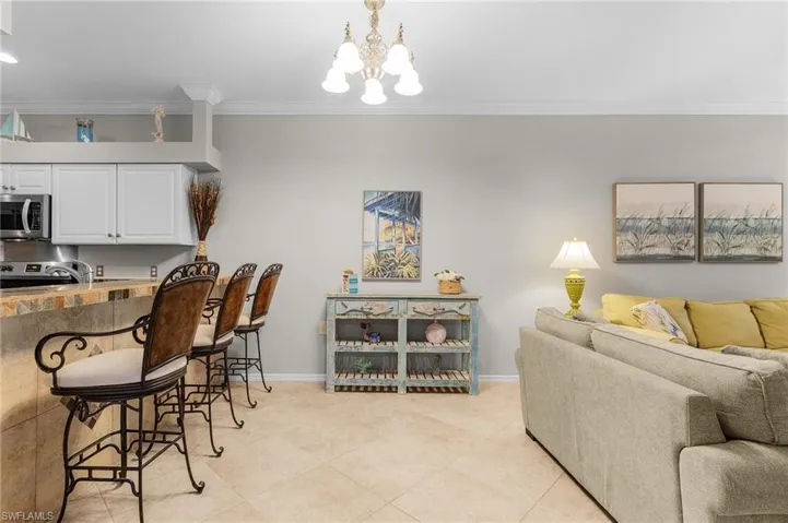 Kitchen with pendant lighting, light tile patterned floors, a notable chandelier, ornamental molding, and white cabinets