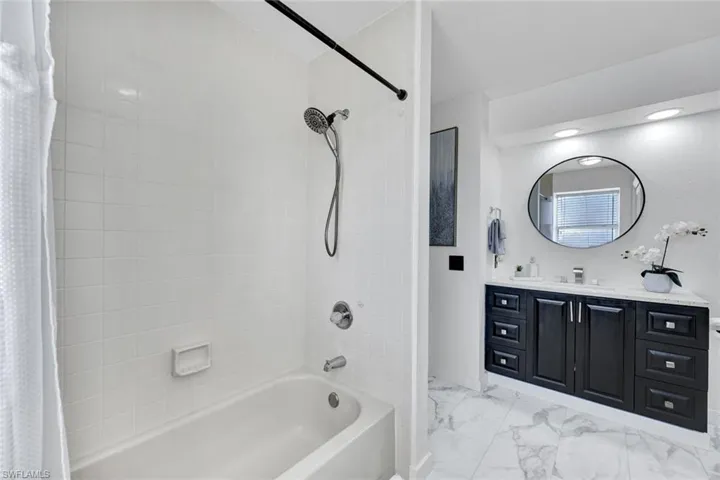 Bathroom with vanity, light marble finish flooring, and shower / tub combo