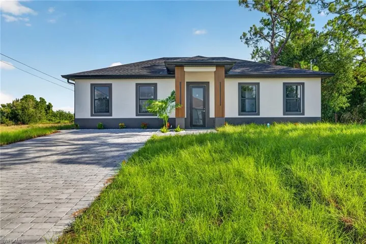 Contemporary single-story residence with a dark gray shingle roof and a cream-colored stucco exterior with a dark gray foundation