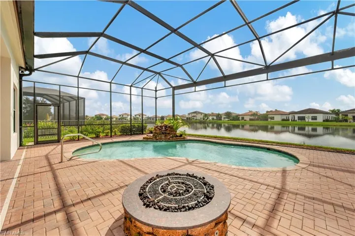 View of pool featuring an outdoor fire pit, a lanai, a water view, and a patio