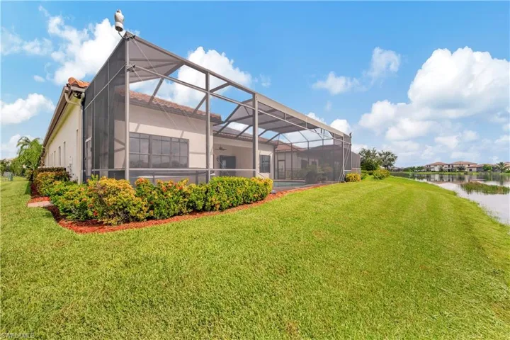 Back of house with a yard and a lanai