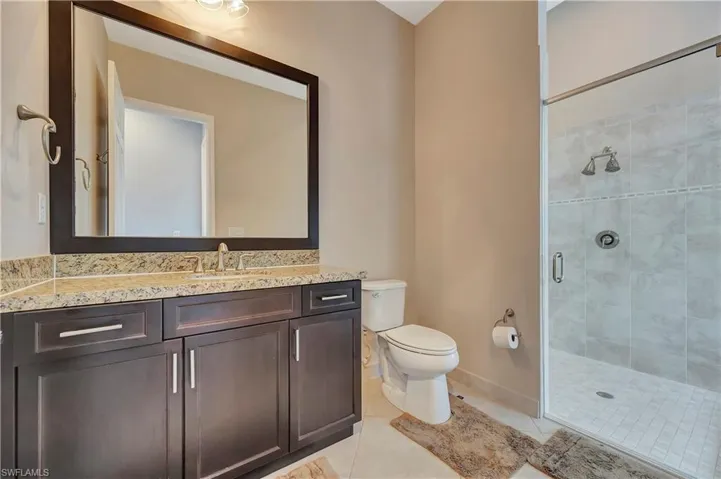 Bathroom with vanity, toilet, a shower with shower door, and tile patterned flooring