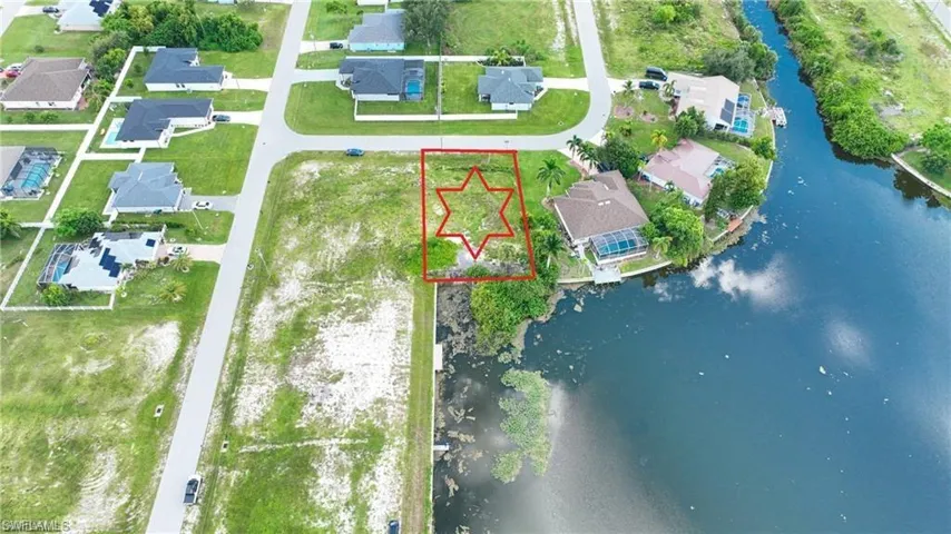 Aerial perspective of suburban area featuring property boundaries highlighted and a large body of water