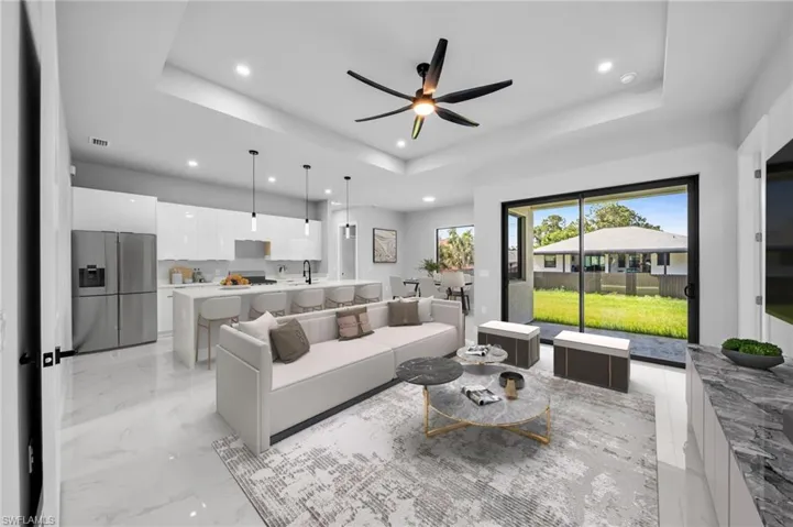Living area with a ceiling fan, a raised ceiling, recessed lighting, and light marble finish floors