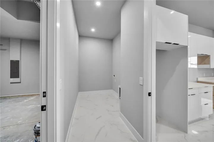 Hallway with light marble finish floors, recessed lighting, and electric panel
