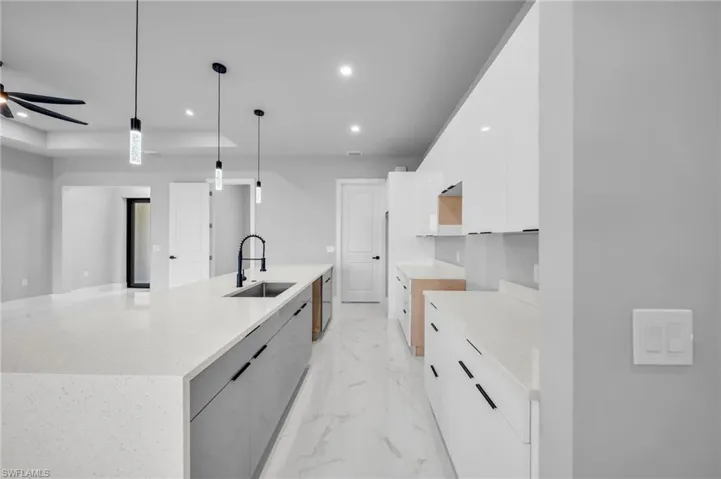 Kitchen featuring white cabinets, recessed lighting, light marble finish flooring, modern cabinets, and decorative light fixtures