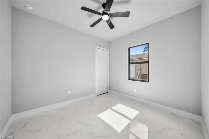 Unfurnished bedroom with marble finish floors and a ceiling fan
