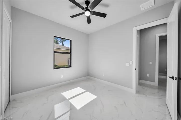 Unfurnished bedroom featuring light marble finish flooring and ceiling fan