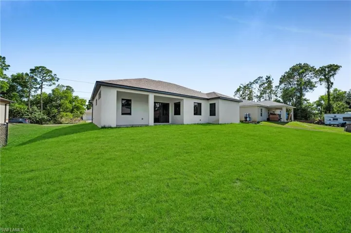 Back of property with a lawn and stucco siding