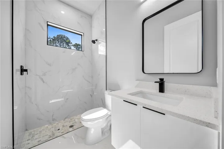 Bathroom with vanity, a marble finish shower, and marble tiled floors
