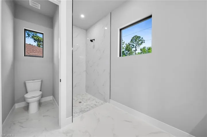Full bath featuring a marble finish shower, marble finish flooring, healthy amount of natural light, and recessed lighting
