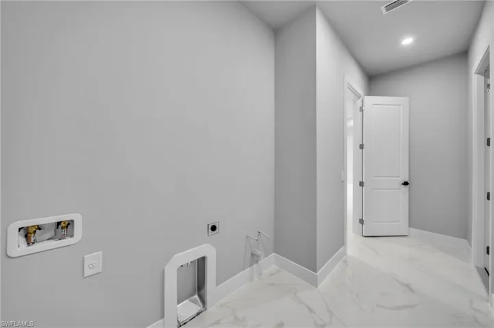 Washroom with hookup for an electric dryer, washer hookup, marble tiled flooring, and recessed lighting