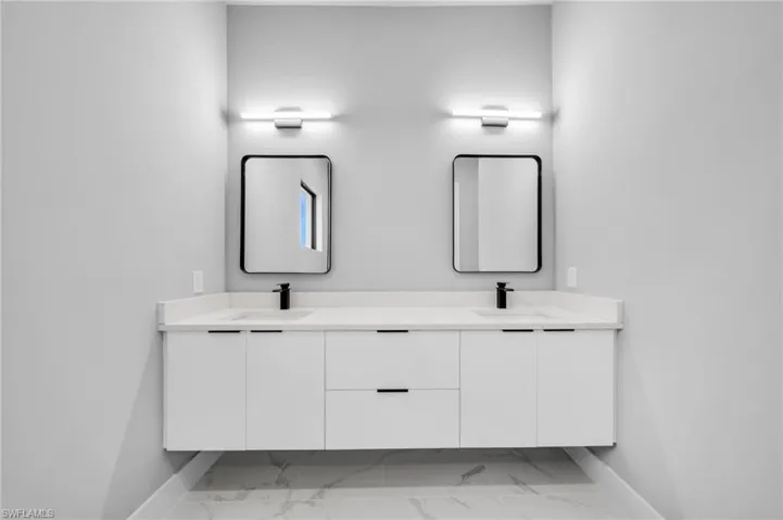 Full bathroom featuring double vanity and light marble finish flooring