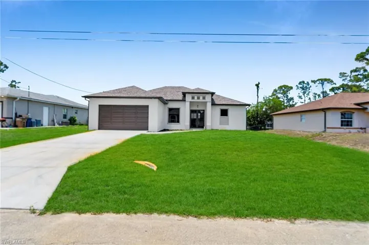 Prairie-style home featuring stucco siding, concrete driveway, and a front yard