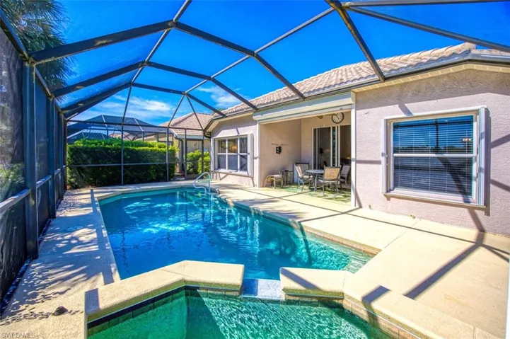 View of swimming pool featuring a patio, a sunroom, a pool with connected hot tub, and a lanai