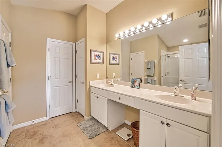 Full bathroom with a stall shower, double vanity, and light tile patterned floors