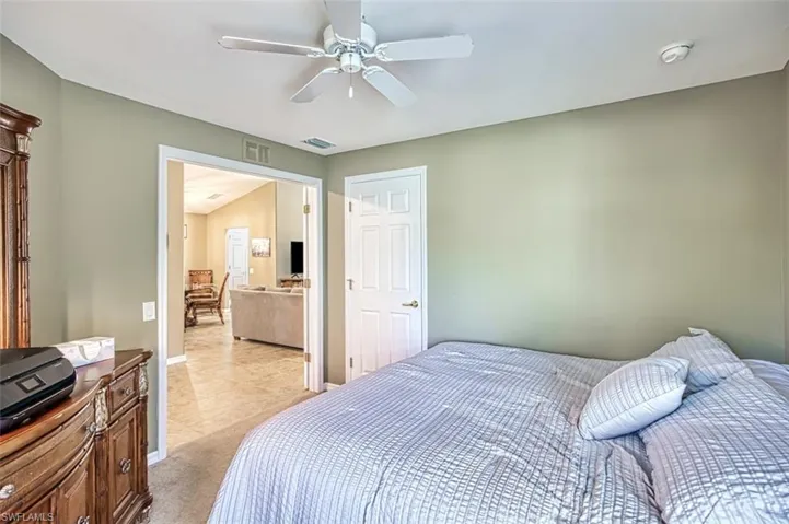 Bedroom with light colored carpet, ceiling fan, and light tile patterned flooring