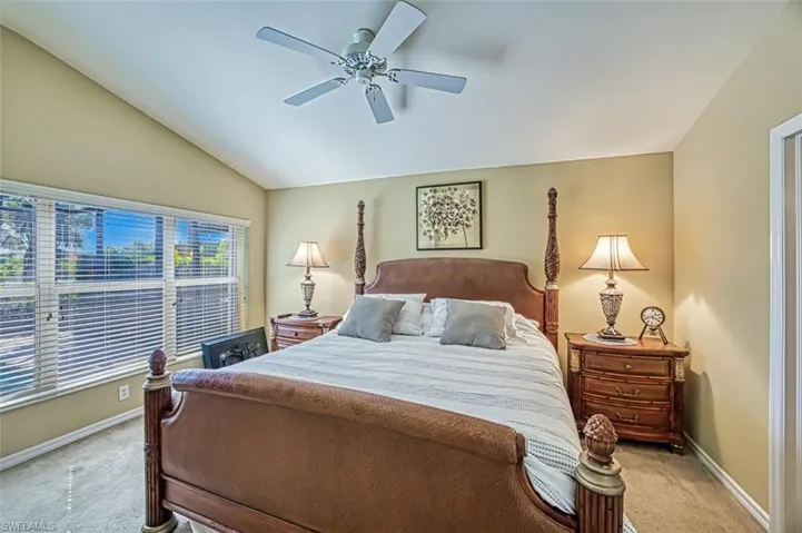 Carpeted bedroom featuring vaulted ceiling and a ceiling fan