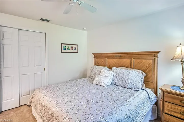 Bedroom with a closet, light carpet, and ceiling fan