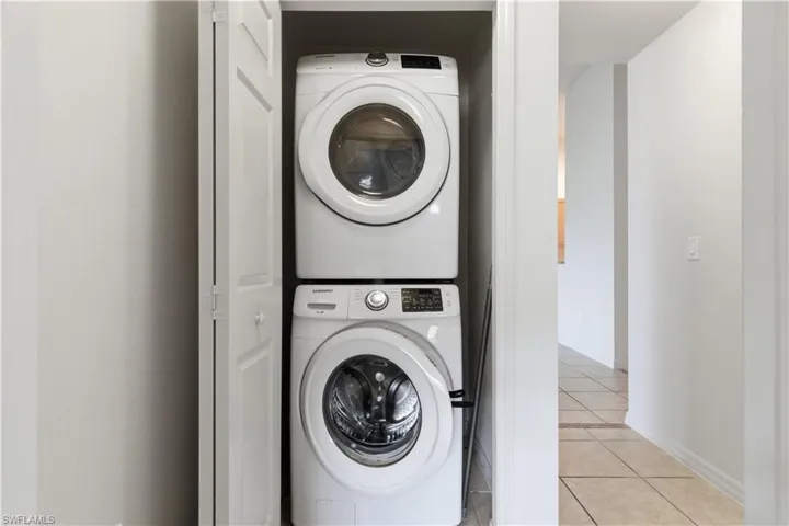 Washroom with light tile patterned floors and stacked washer and clothes dryer