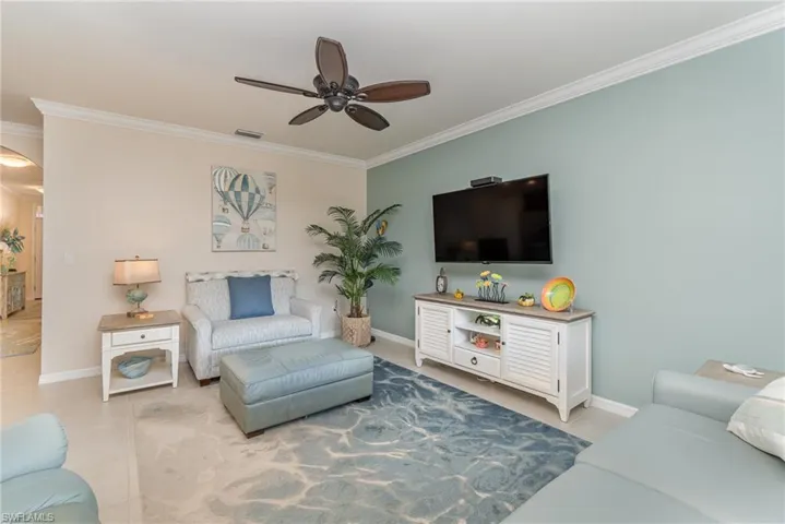 Tiled living room featuring crown molding and ceiling fan