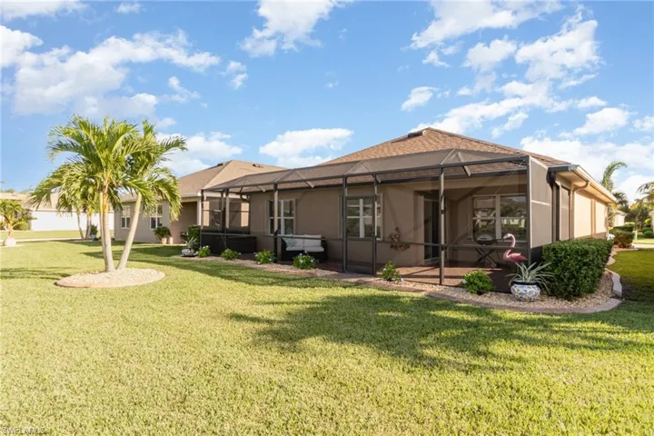 Rear view of property featuring a lawn and screened enclosure