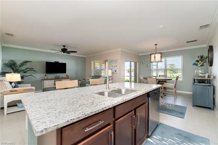 Kitchen with dishwasher, hanging light fixtures, sink, an island with sink, and ceiling fan