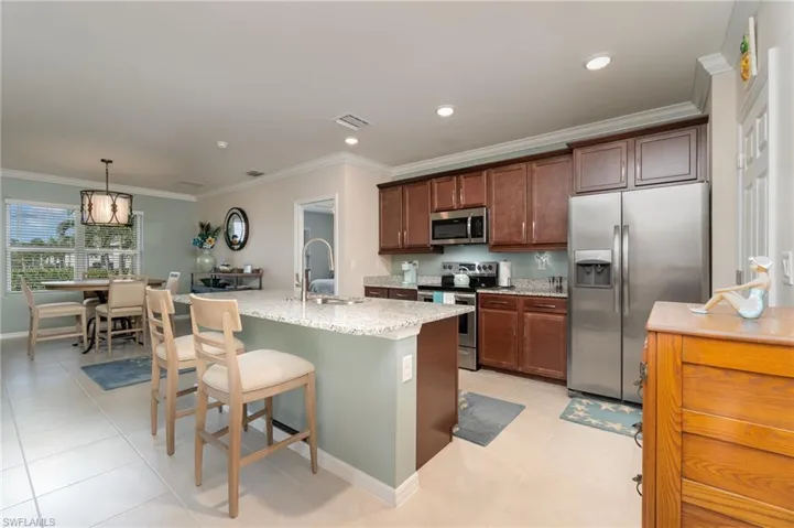 Kitchen with stainless steel appliances, a center island with sink, sink, and crown molding