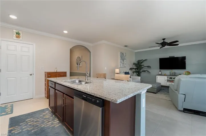Kitchen with stainless steel dishwasher, a center island with sink, sink, and brown cabinetry