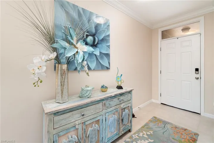 Tiled entrance foyer featuring crown molding