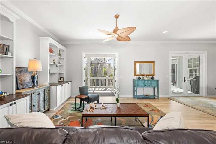 Living room with french doors, light wood-type flooring, ceiling fan, and crown molding