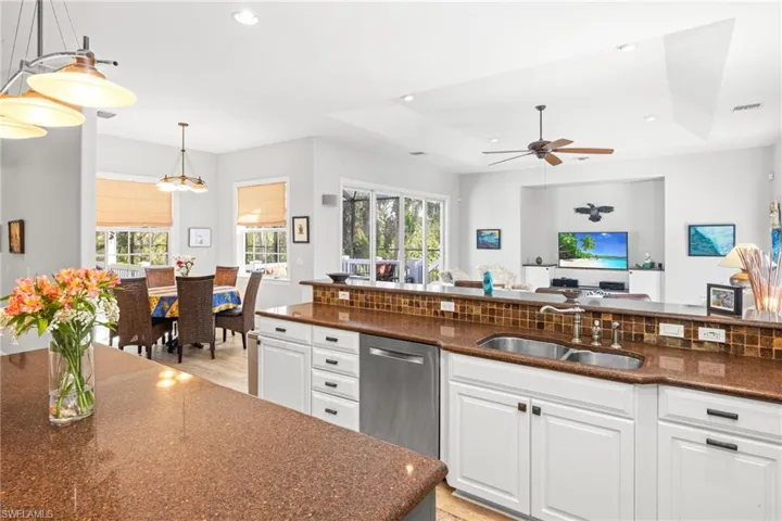 Kitchen with white cabinets, decorative light fixtures, a wealth of natural light, and sink