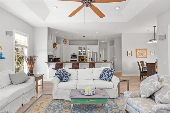 Living room featuring light wood-type flooring, a tray ceiling, and ceiling fan