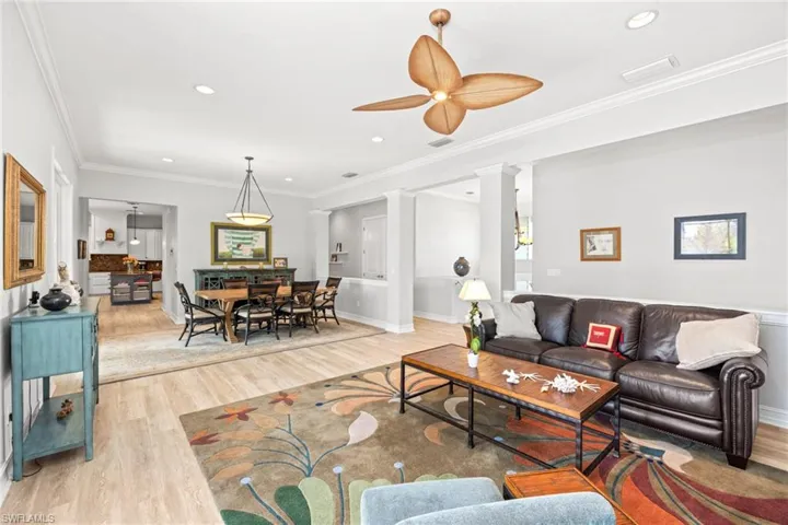 Living room with hardwood / wood-style flooring, ceiling fan, ornate columns, and crown molding