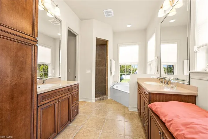 Bathroom featuring tile patterned floors, 2 vanities, and a healthy amount of sunlight