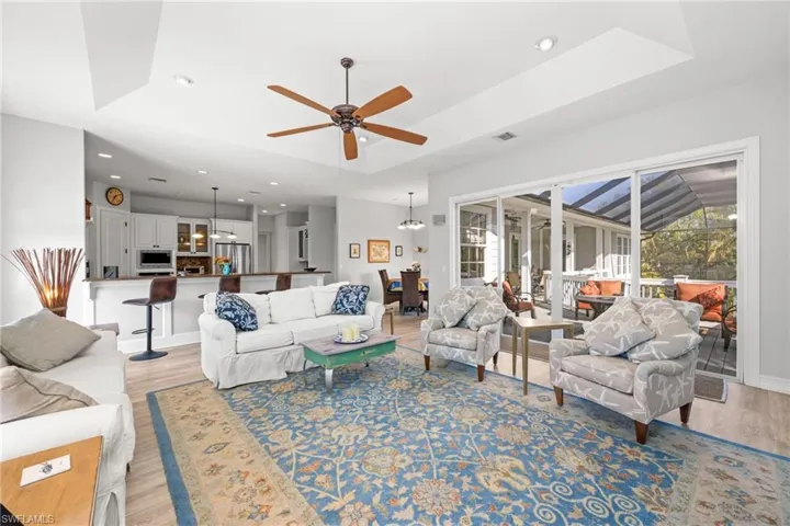 Living room featuring ceiling fan with notable chandelier and light wood-type flooring