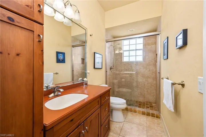Bathroom with tile patterned floors, vanity, a shower with shower door, and toilet
