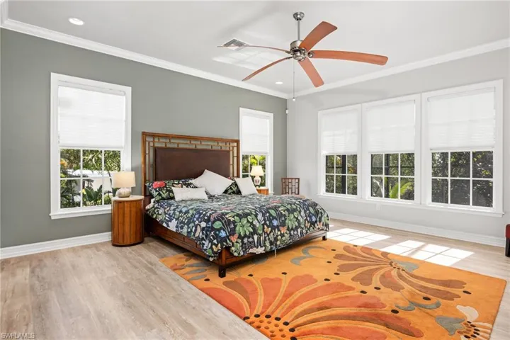 Bedroom with multiple windows, ceiling fan, light hardwood / wood-style flooring, and crown molding
