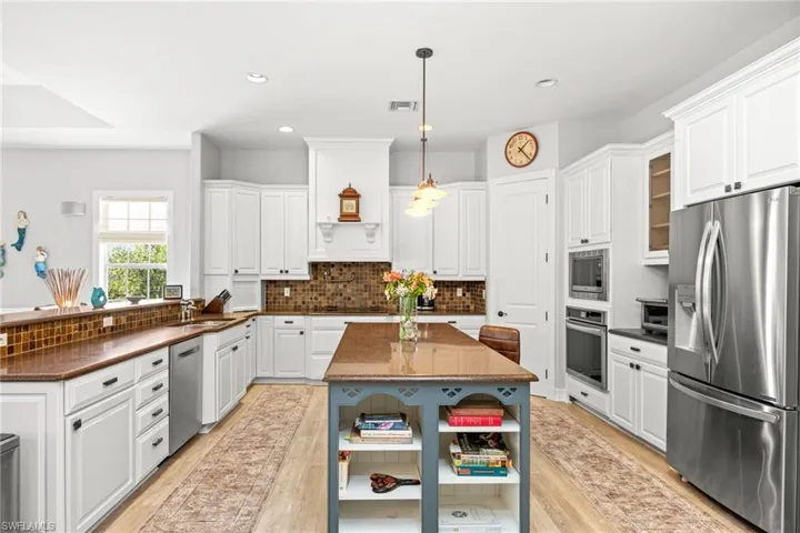 Kitchen featuring white cabinets, hanging light fixtures, light wood-type flooring, and appliances with stainless steel finishes