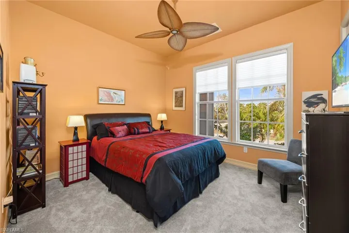 Bedroom with light carpet, multiple windows, and ceiling fan