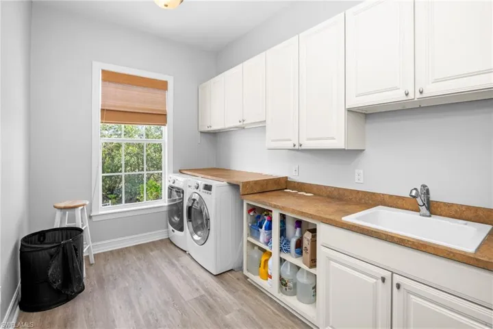 Laundry room with washer and dryer, light hardwood / wood-style floors, cabinets, and sink