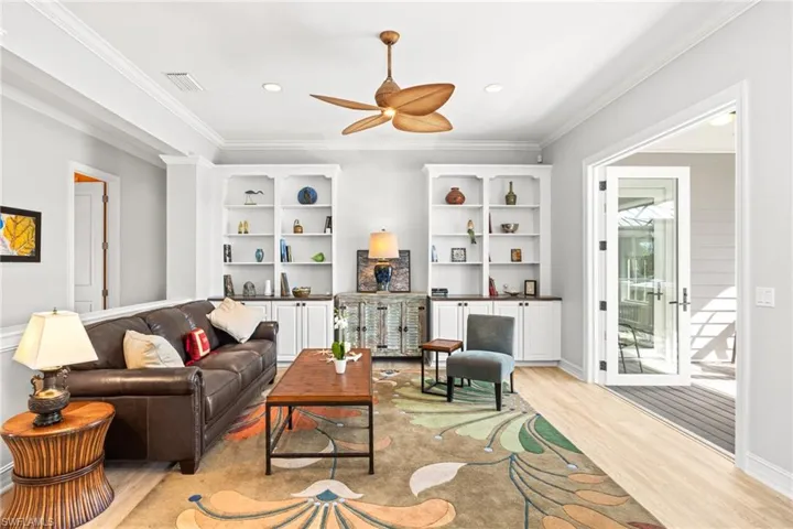 Living room featuring ceiling fan, a healthy amount of sunlight, light wood-type flooring, and ornamental molding