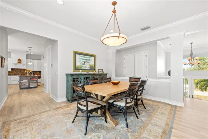 Dining room featuring an inviting chandelier, ornamental molding, and light wood-type flooring