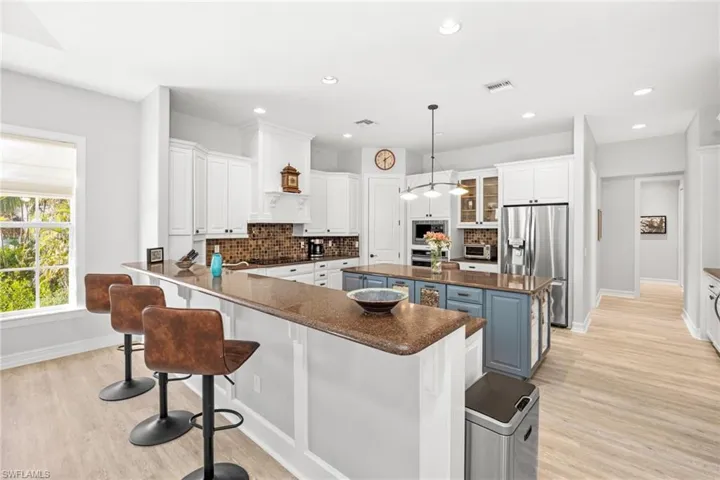 Kitchen featuring a center island, white cabinetry, stainless steel refrigerator with ice dispenser, and tasteful backsplash