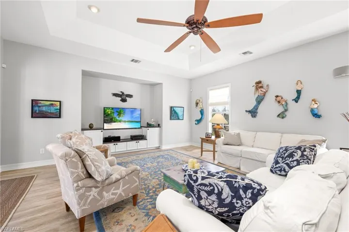 Living room featuring a raised ceiling, light hardwood / wood-style flooring, and ceiling fan