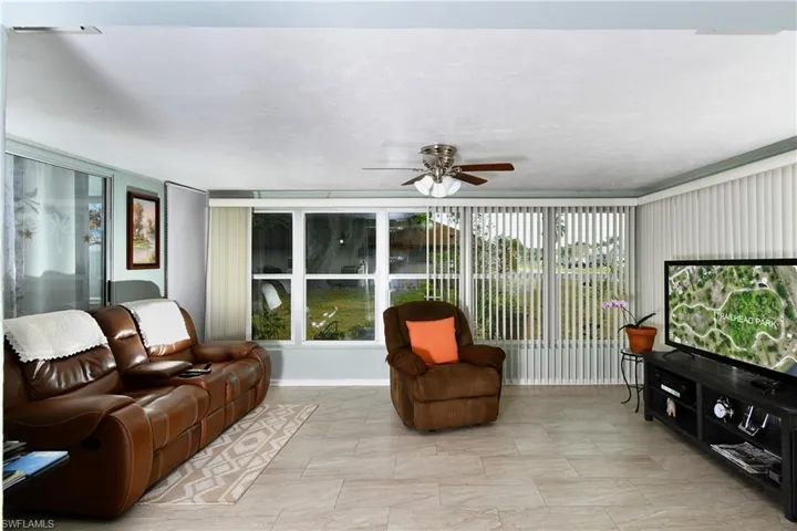 Teather like living room, with great view ceiling fan and light tile flooring featuring a wealth of natural light