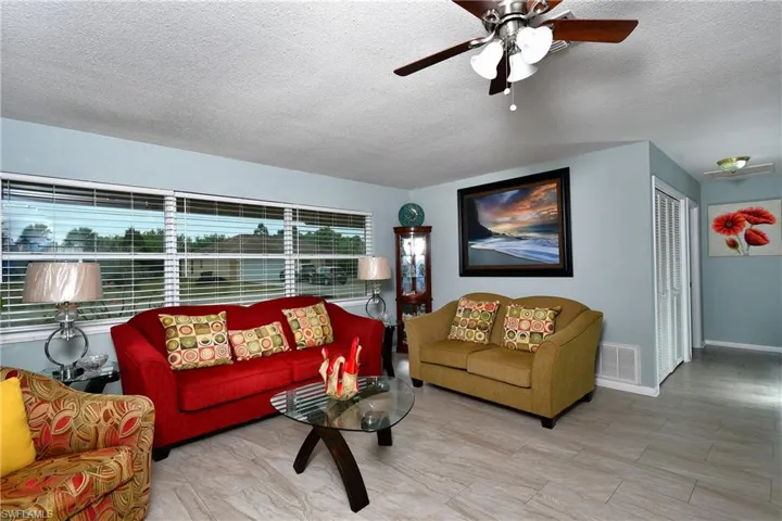 Living room with ceiling fan, featuring a wealth of natural light