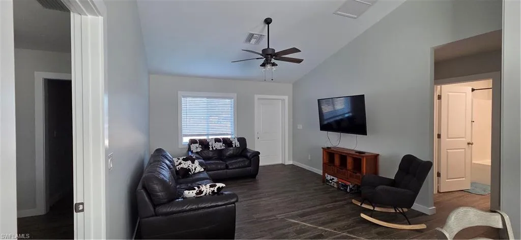 Living room featuring lofted ceiling, dark wood-type flooring, and a ceiling fan