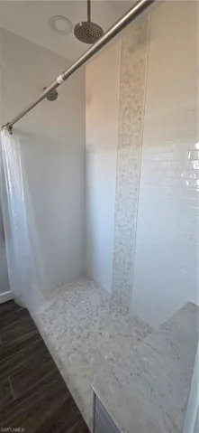 Full bath featuring a custom stall shower and dark wood-style flooring