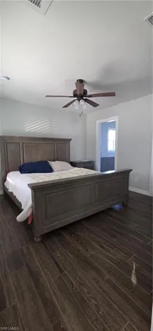 Bedroom featuring dark wood-style flooring, ceiling fan, and ensuite bathroom